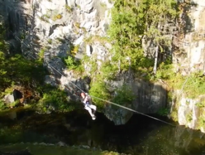 Man on a zip-line above a lake. Acrosphere.